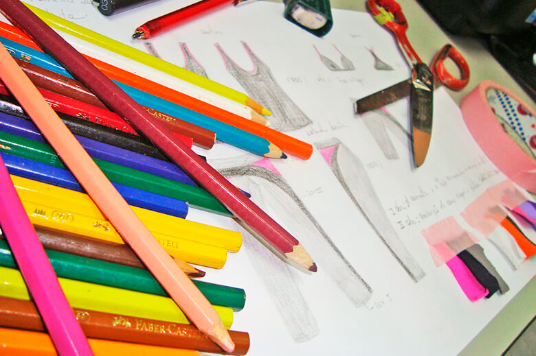 Desenho de um croqui com vários lápis de cor e tesoura ao redor