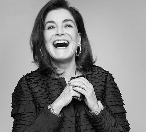 Gloria Kalil de casaco preto dando risada