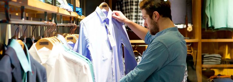 Homem olhando camisas em araras