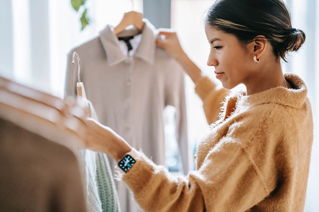 Mulher escolhendo roupas com peças no estilo slow fashion