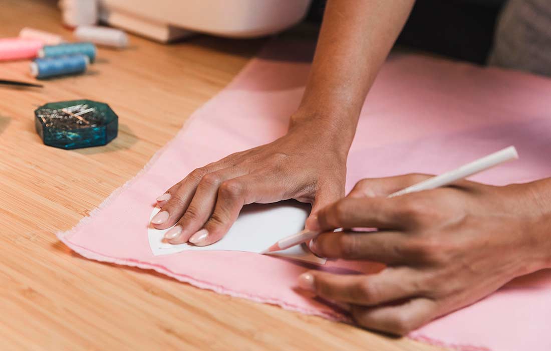 mulher trabalhando na modelagem de roupas em uma mesa de confecção