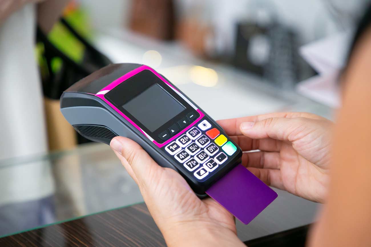 Uma mulher segurando uma máquina de cartão de crédito, mostrando que é um benefício da psicologia de vendas