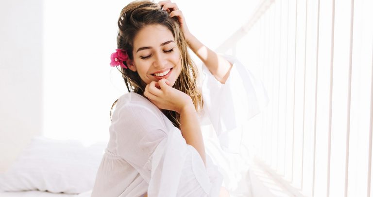 mulher sorridente vestido roupas fuidas em tons claros, no estilo da moda comfy