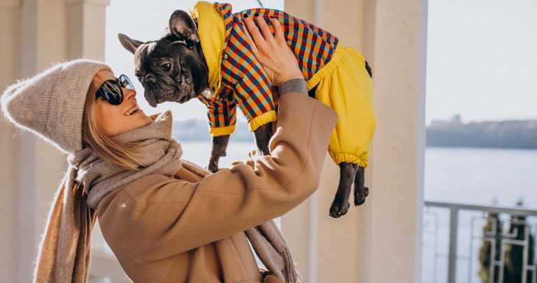 mulher segurando um cachorro vestido com roupinhas de moda pet