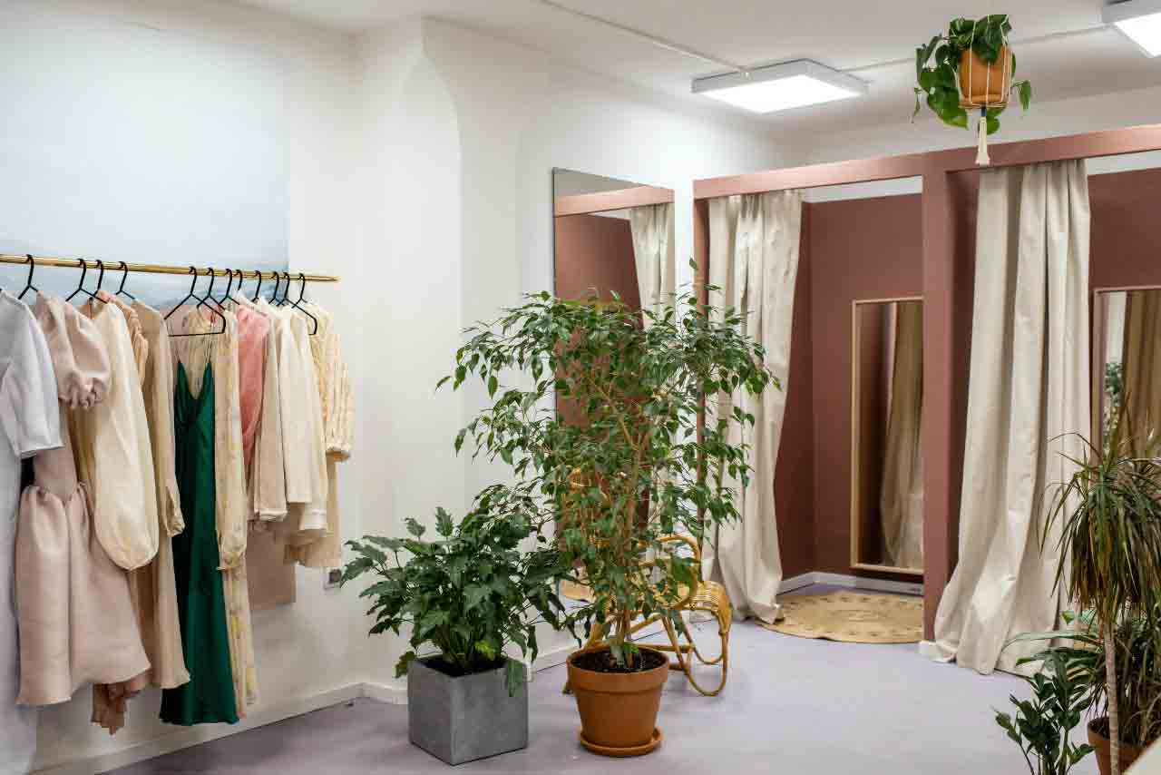 imagem de loja de roupas decorada com plantas, fazendo referencia a moda sustentavel