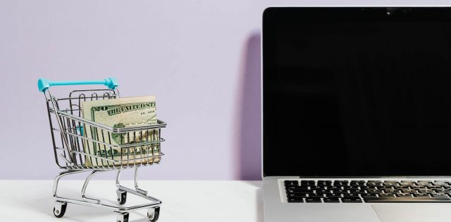 imagem mostrando um notebook e um carrinho de mercado em miniatura com dinheiro dentro, representando o conteúdo se como aumentar as vendas online