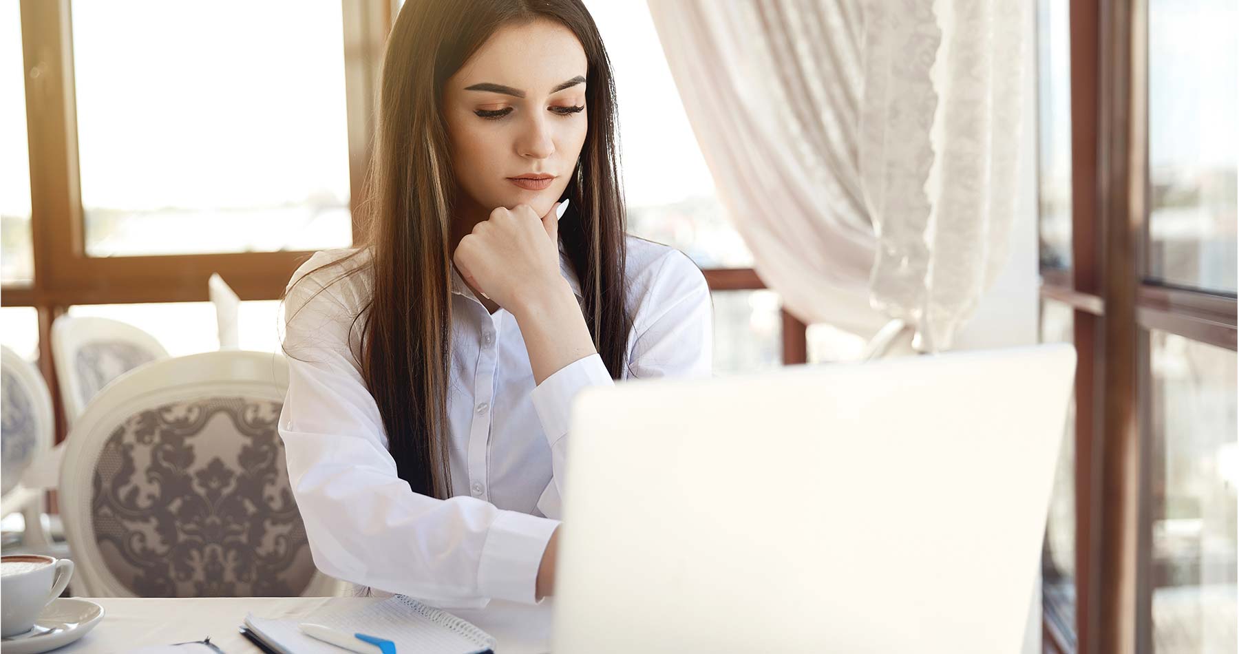 mulher em frente ao computador, com imagem pensativa, sobre como lidar om inadimplência