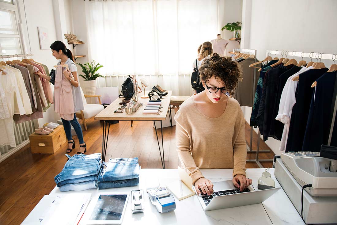 mulher dona de confecção, em seu escritório, considerando por que investir em moda atemporal