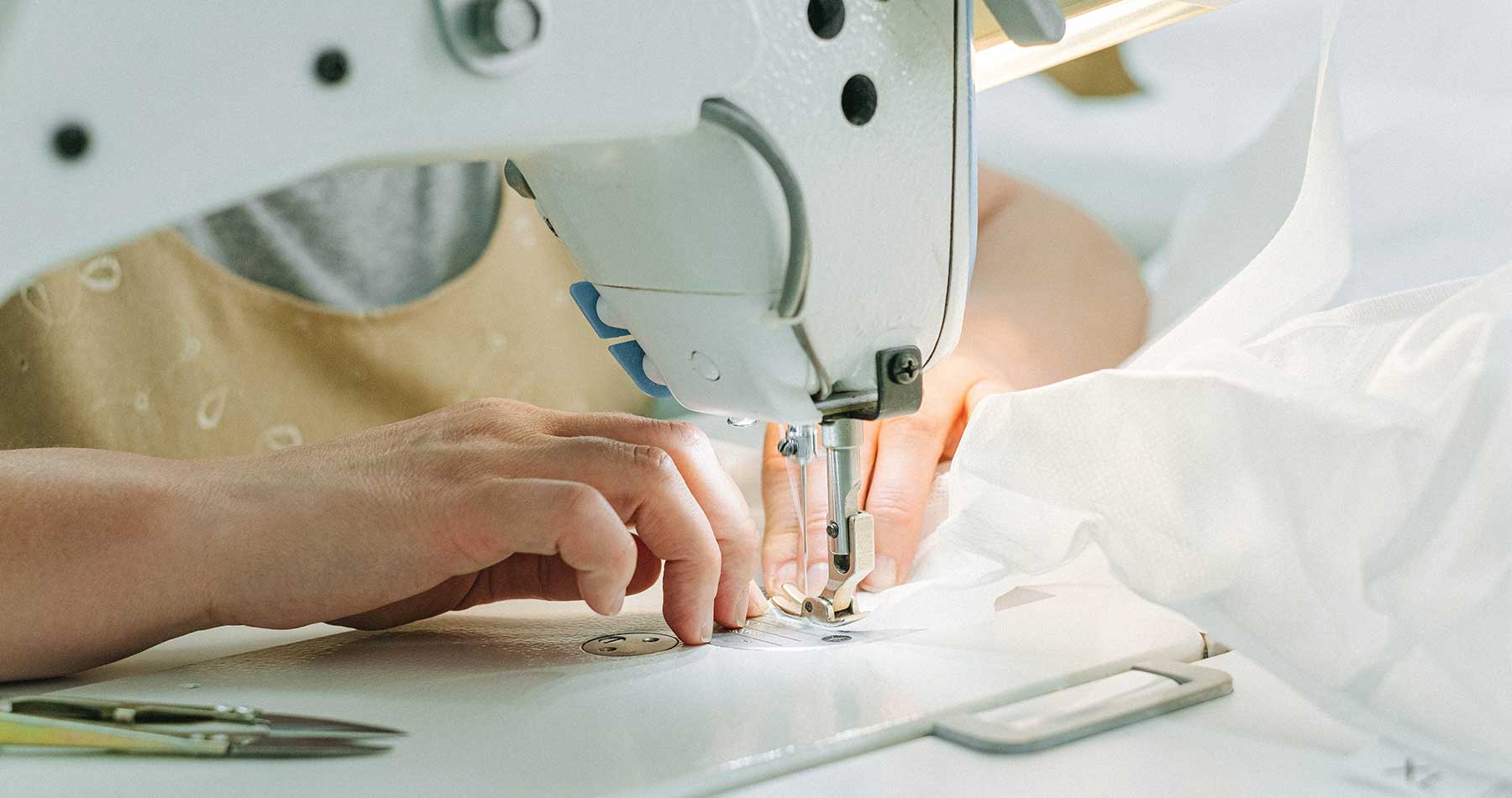 close de uma mulher costurando em uma máquina, representando o trabalho das facções de costura