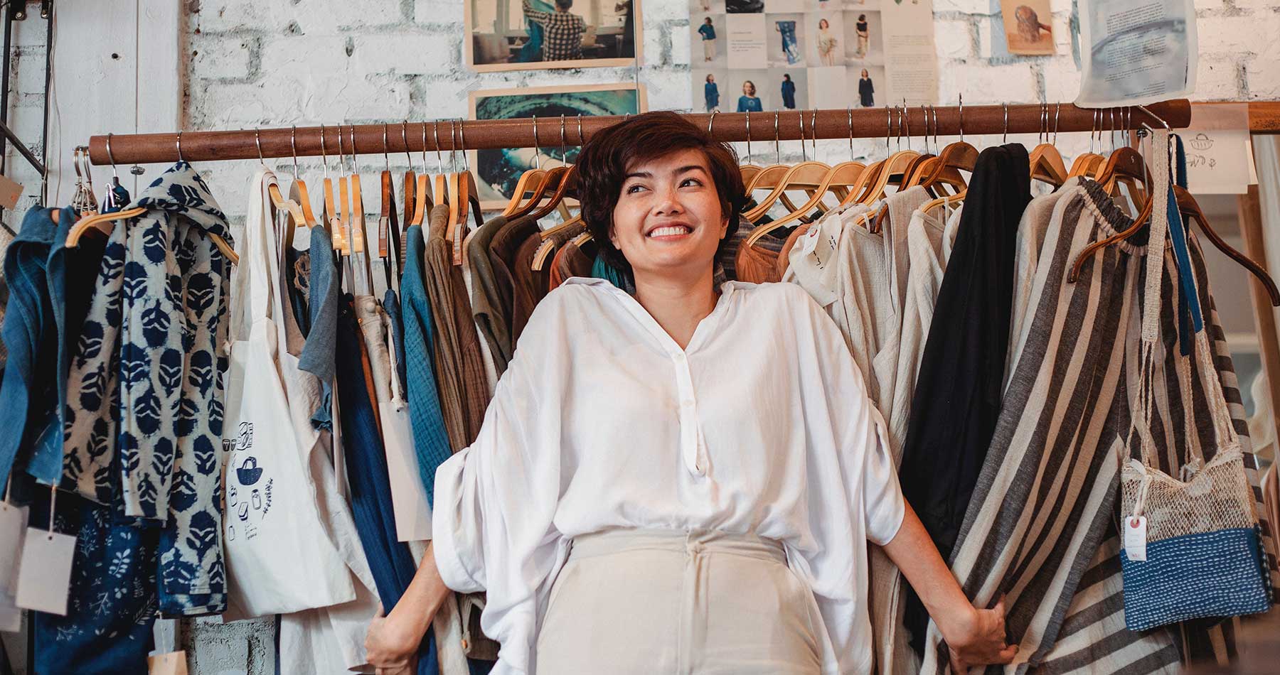 mulher feliz com suas peças após realizar planejamento e produção de sua coleção de moda