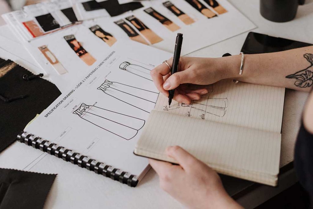 mulher fazendo desenhos para coleção de moda