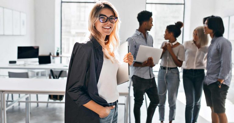 foto com uma mulher empreendedora ao centro, representando a gestão de negócios de moda, ao fundo aparecem mais quatro pessoas conversando