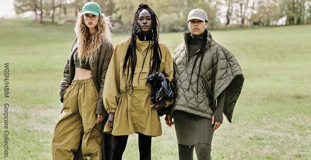 três mulheres em um campo usando roupas no estilo gorpcore