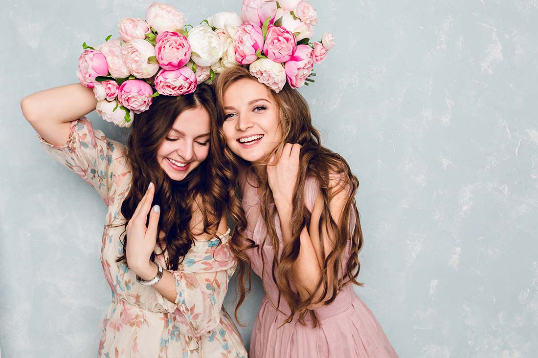 Duas mulheres com flores na cabeça e vestindo roupas no estilo romântico dentro dos 7 estilos universais de moda