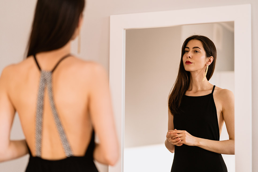 Mulher se olhando no espelho vestindo preto no estilo de moda sensual dentro dos 7 estilos universais de moda