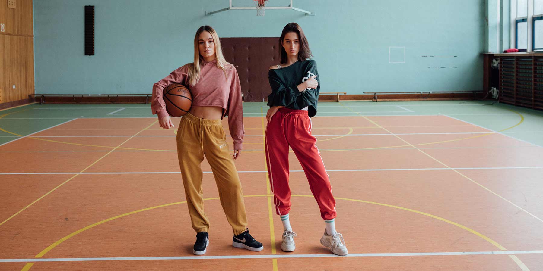 Duas jovens esportistas na quadra de basquete vestindo roupas no estilo activewear