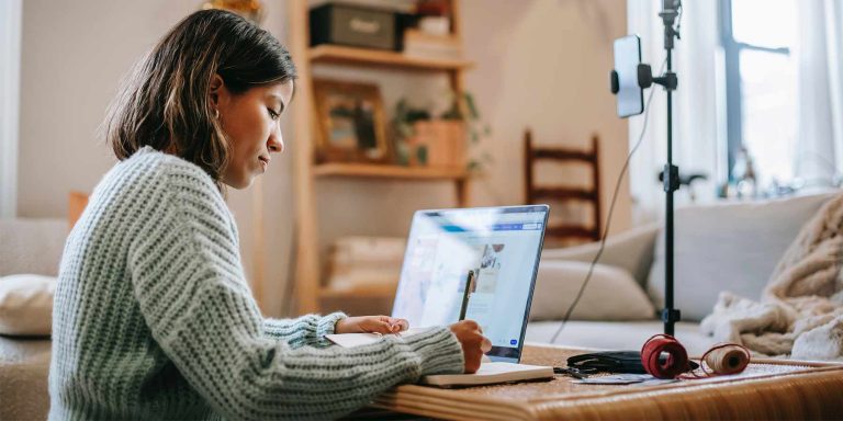 Mulher de meia idade sentada me frente ao computador conferido as linhas editoriais das suas redes sociais