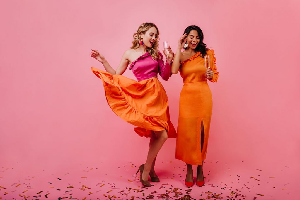 Duas mulheres bonitas brindando com looks coloridos dentro do circulo cromático