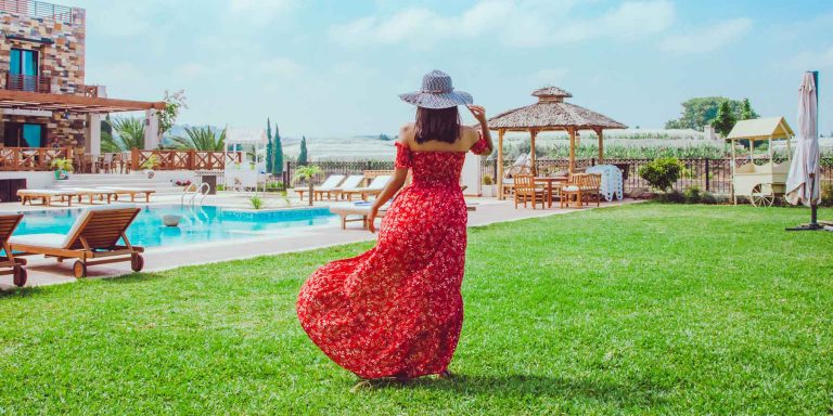 Mulher jovem morena andando próximo a uma piscina usando um vestido vermelho mostrando como aplicar o lastex