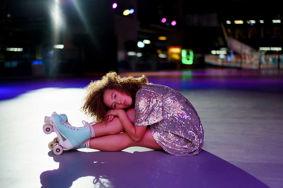 patinadora sentada na pista, com um vestido brilhante