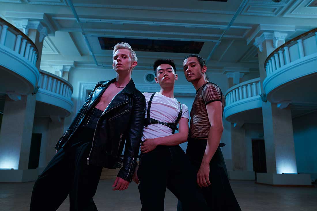 três homens usando roupas no estilo glam rock