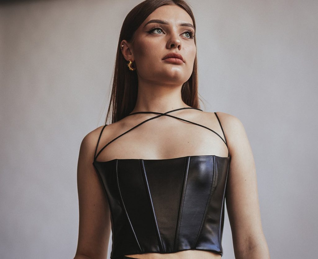 Jovem com roupa em couro preta mostrando