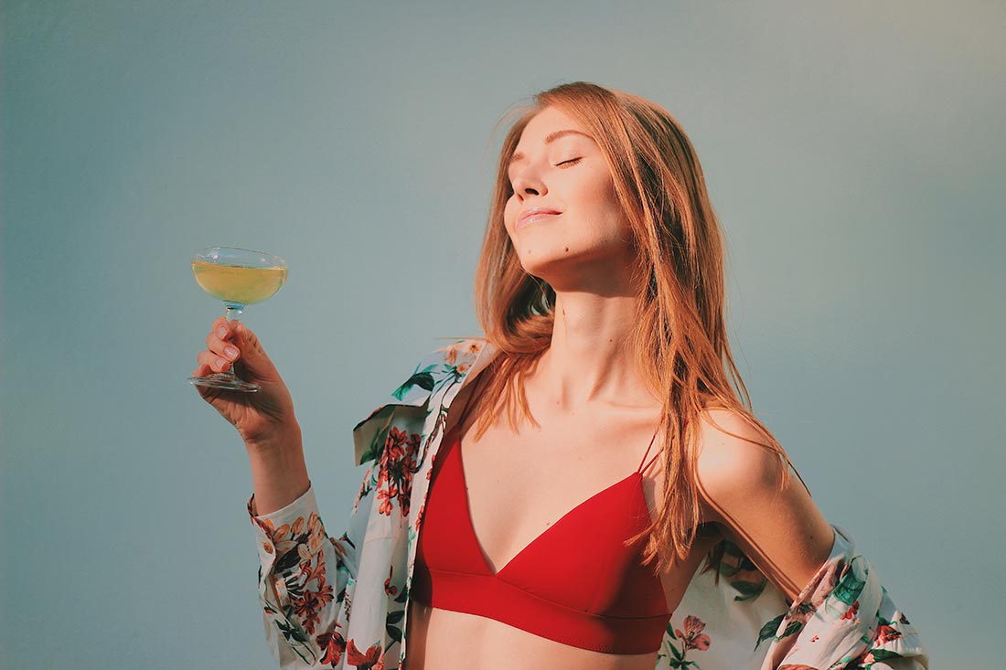 Mulher jovem com taça de espumante, camisa de botão e  lingerie no Street Style.