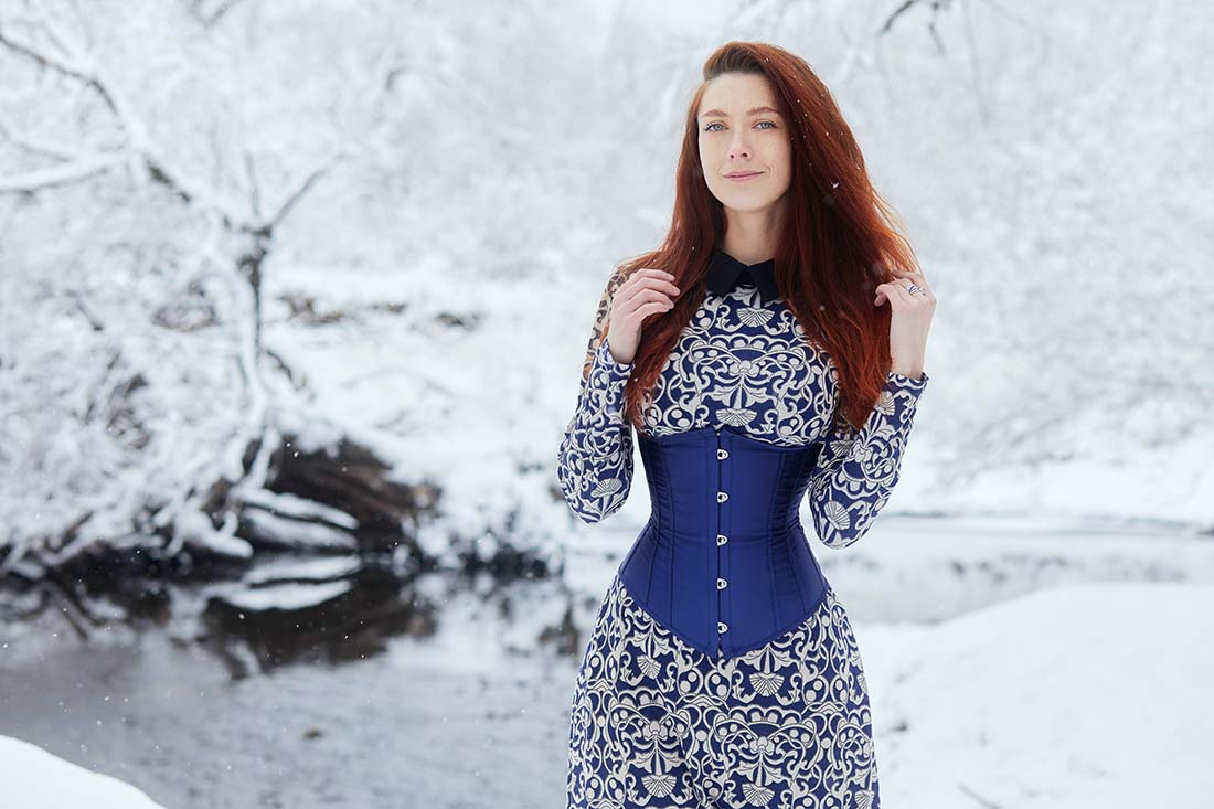 Mulher no meio da neve com vestido azul mostrando looks com corset