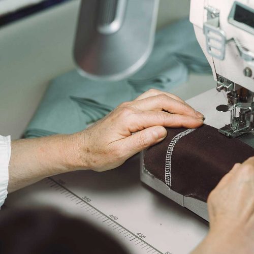 mulher costurando uma etiqueta em uma peça de roupas, seguindo as diretrizes de etiquetagem têxtil