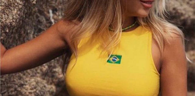 foto close de mulher loira usando top amarelo com uma bandeira do Brasil, uma das possibilidade de looks com lingerie para a Copa do Mundo