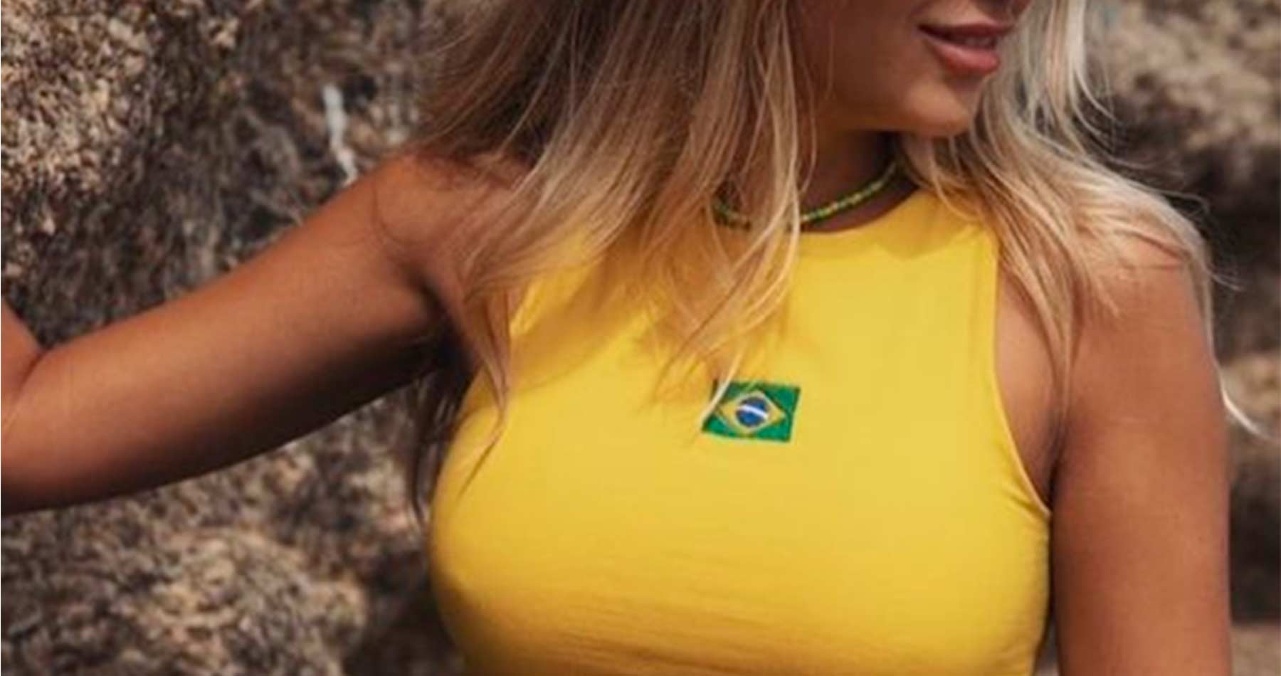 foto close de mulher loira usando top amarelo com uma bandeira do Brasil, uma das possibilidade de looks com lingerie para a Copa do Mundo
