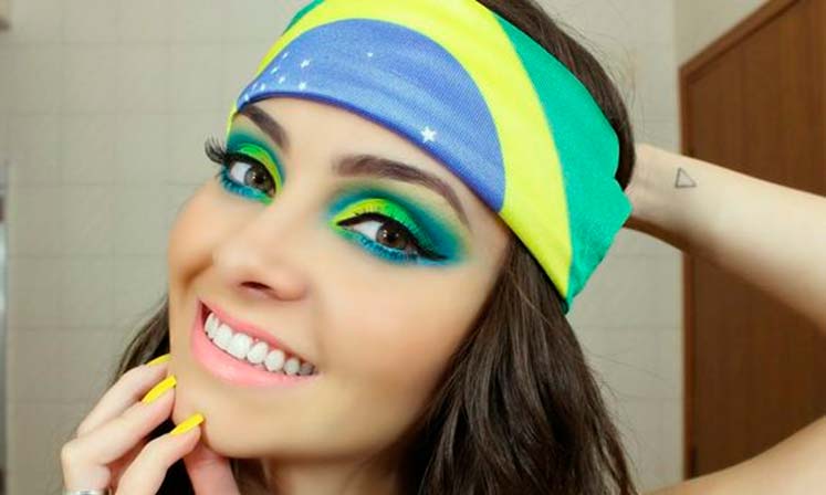 mulher usando faixa no cabelo com a bandeira do Brasil e maquiagem nos tons da bandeira, seguindo a estética Brasilcore para a copa do mundo