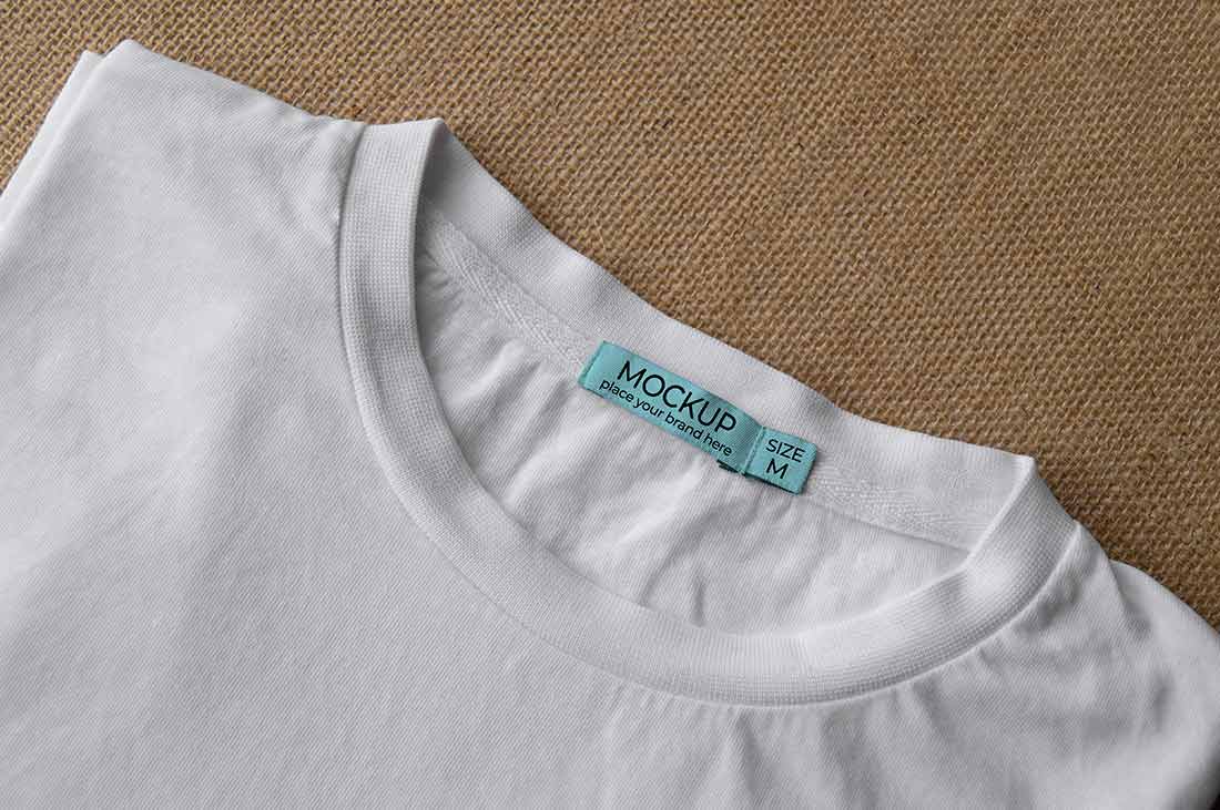imagem close de uma camiseta branca, mostrando a etiqueta que foi produzida de acordo com as regras de etiquetagem têxtil