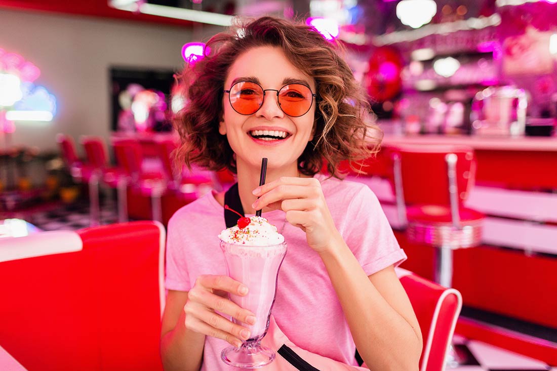 Mulher tomando suco em ambiente totalmente rosa uma das cores tendência de moda para 2023