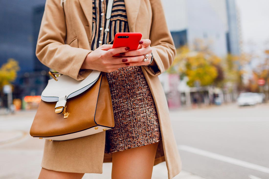 Mulher no celular aparecendo as roupas tendência de moda para 2023